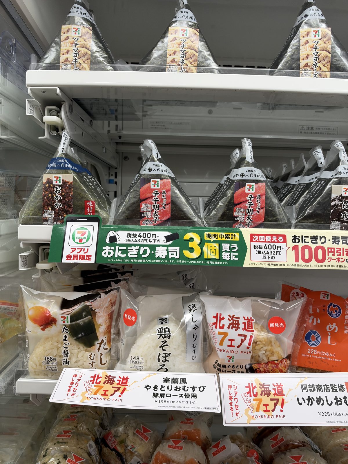 Three rice balls for 100 yen off, next to a regional fair display.